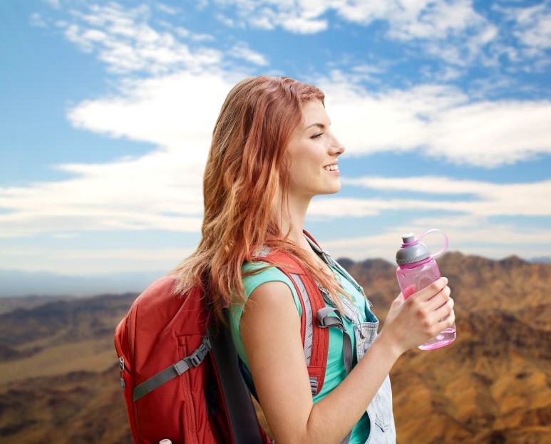 Γυναίκα ταξιδιώτης στη φύση με μπουκάλι νερό στα χέρια της