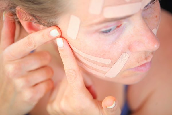 Γυναίκα με ταινίες στο πρόσωπό της για beauty-face taping